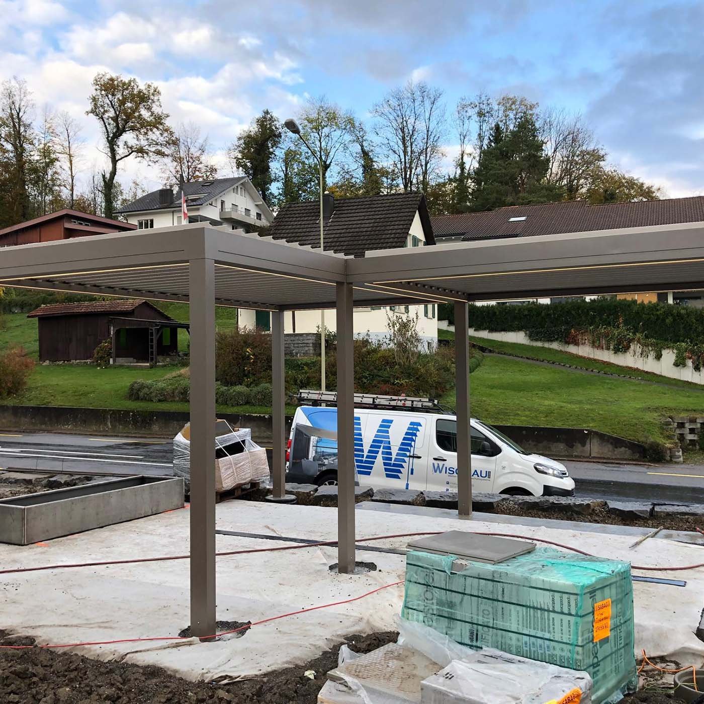 Freistehendes Lamellendach im Rohbau auf einer Baustelle, daneben ein Servicefahrzeug von Wisobau