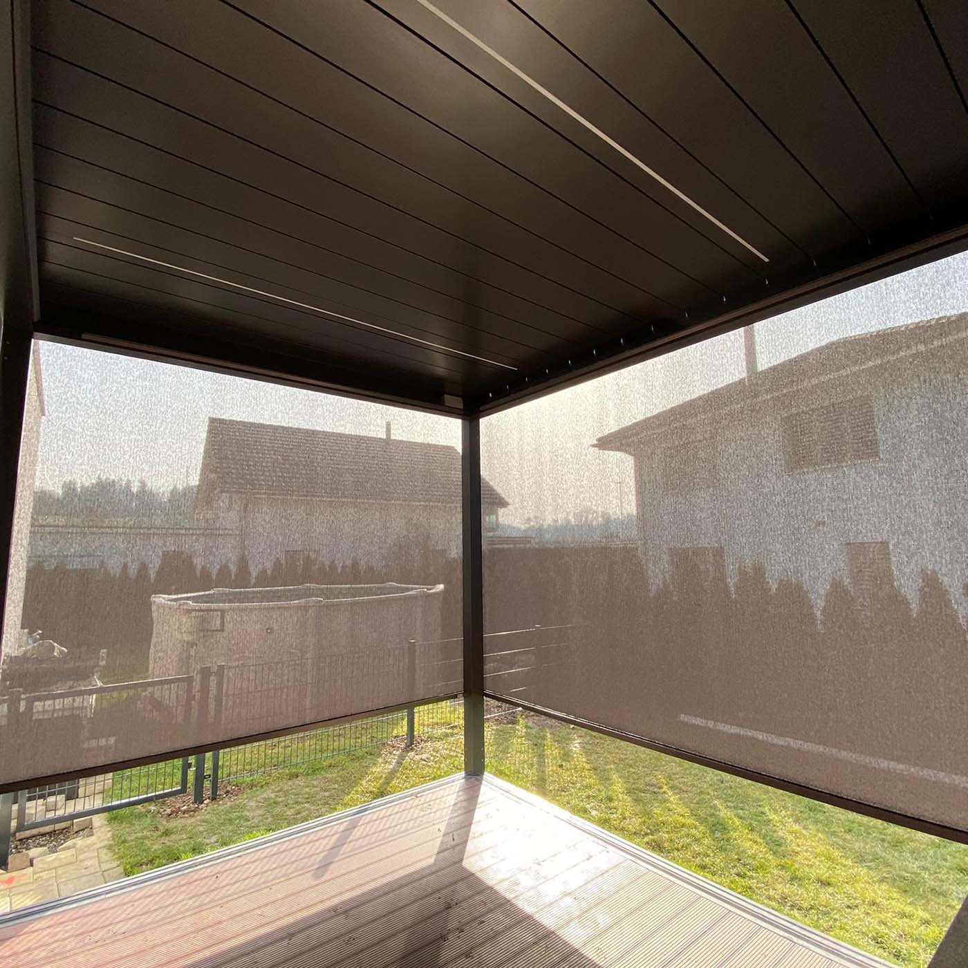 Untersicht eines Lamellendachs mit heruntergelassenen Screens am Abend