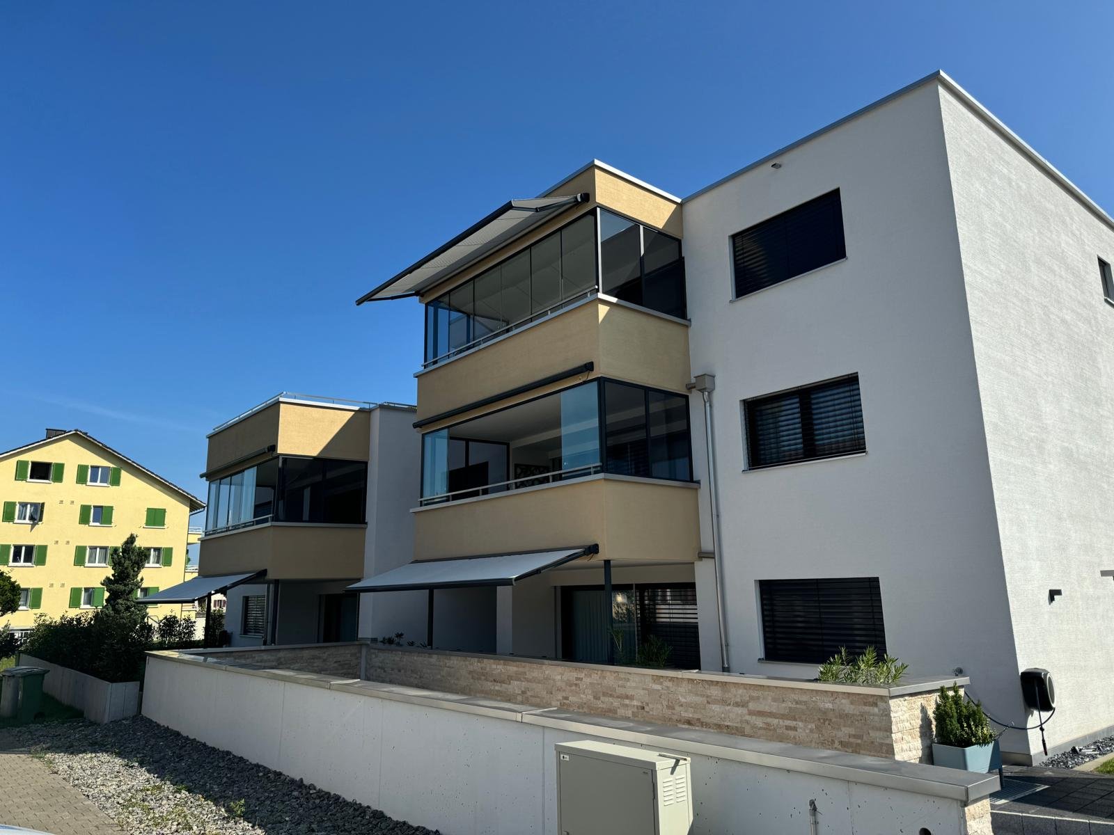Mehrfamilienhaus mit Gelenkarmmarkisen und Raffstoren an der Fassade