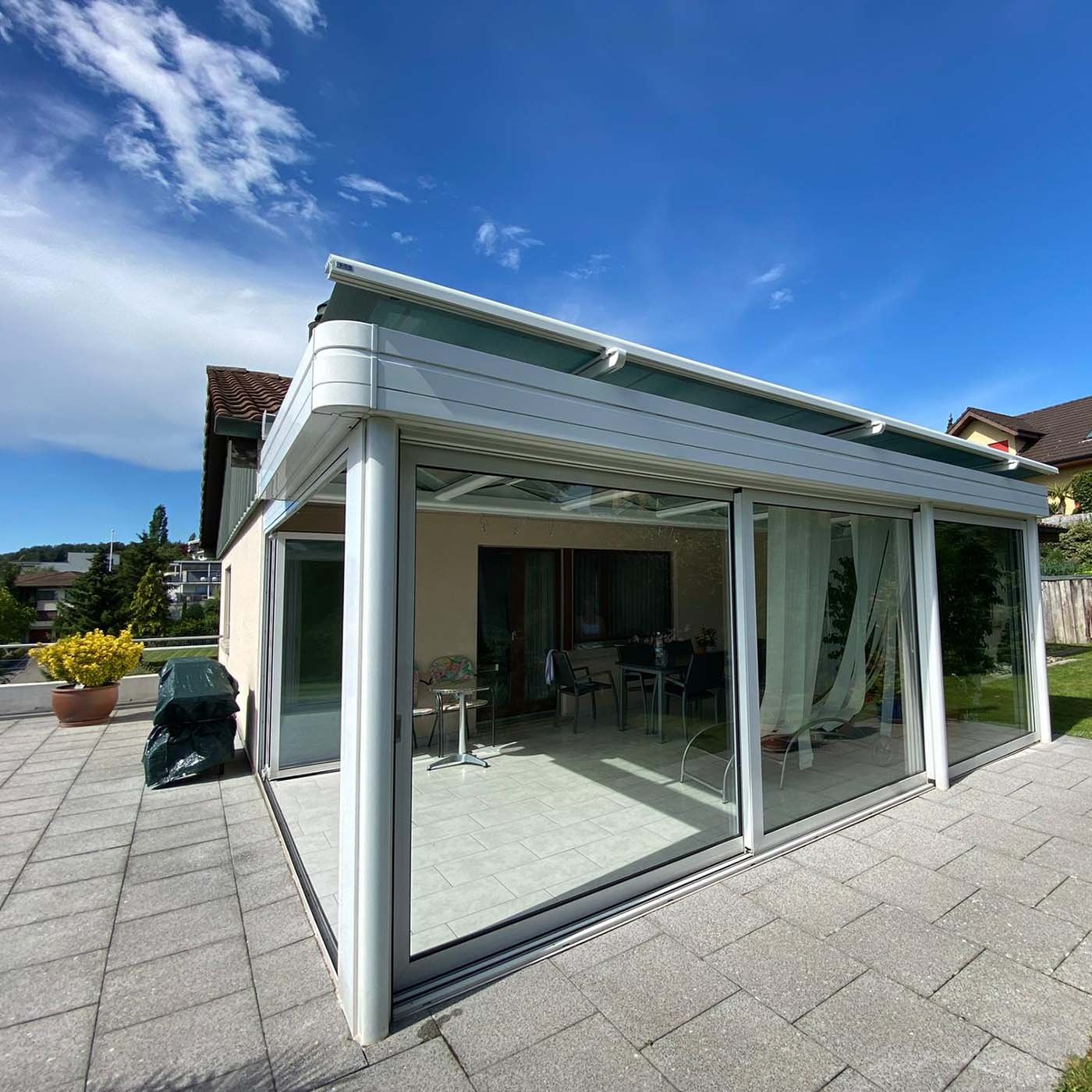Verglaster Terrassenanbau mit weissem Rahmen und Glas-Schiebeelementen